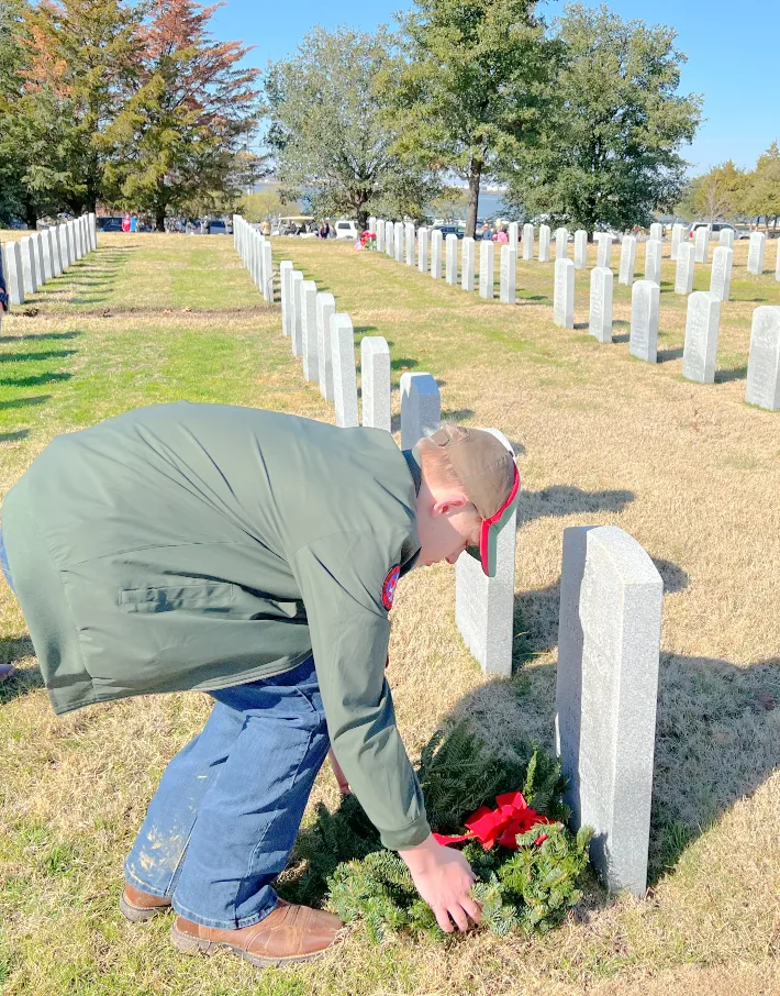 A young man placing a wreath on a grave